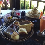 Fresh fruit plate, basket of bread and muffins with fresh jams, a fresh tropical fruit smoothie, Balinese coffee or tea and eggs with bacon.